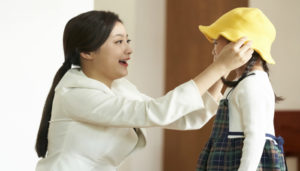 子どもに防止を被せる母親